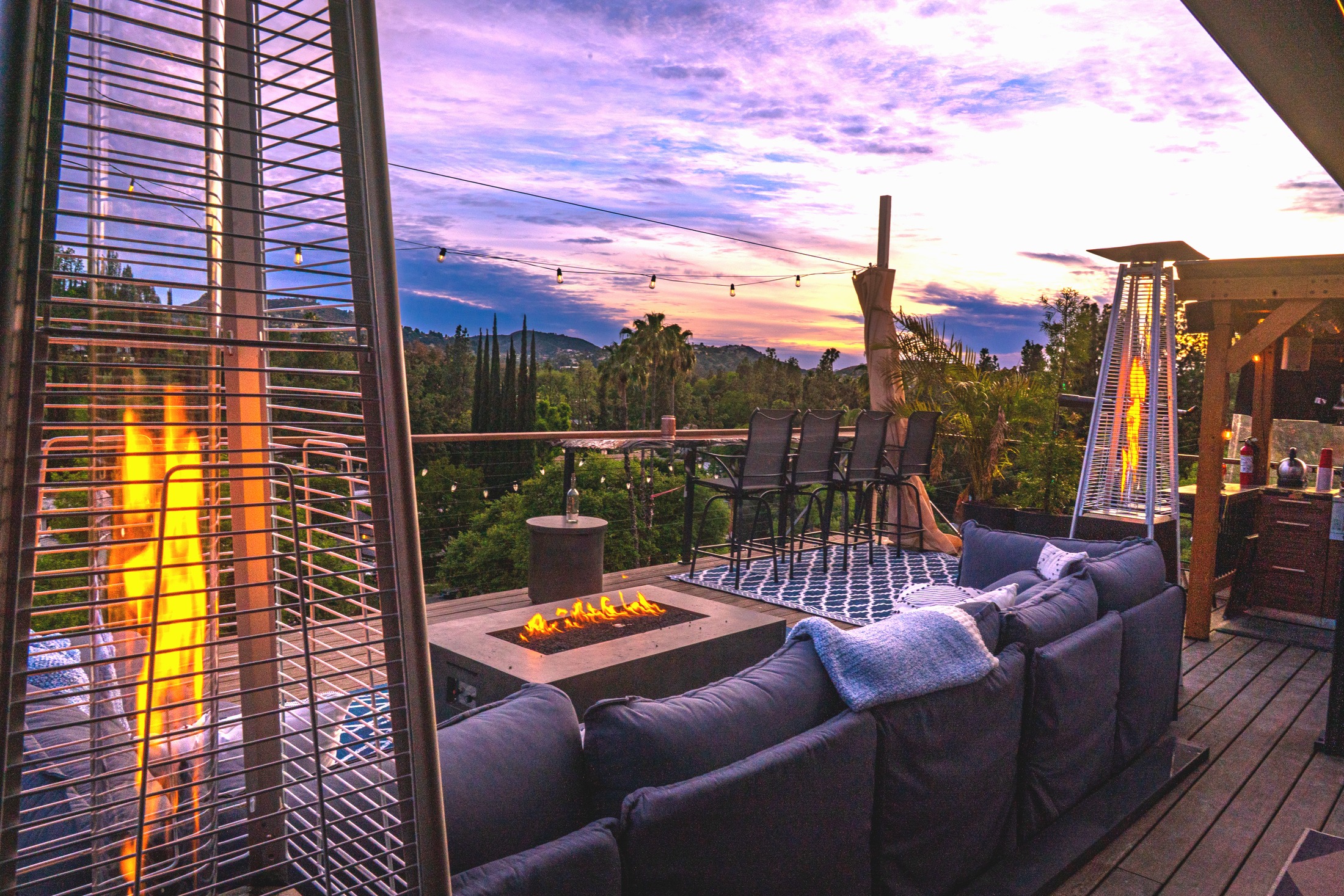 Private deck venue with couches, string lights, fire, and open sunset sky